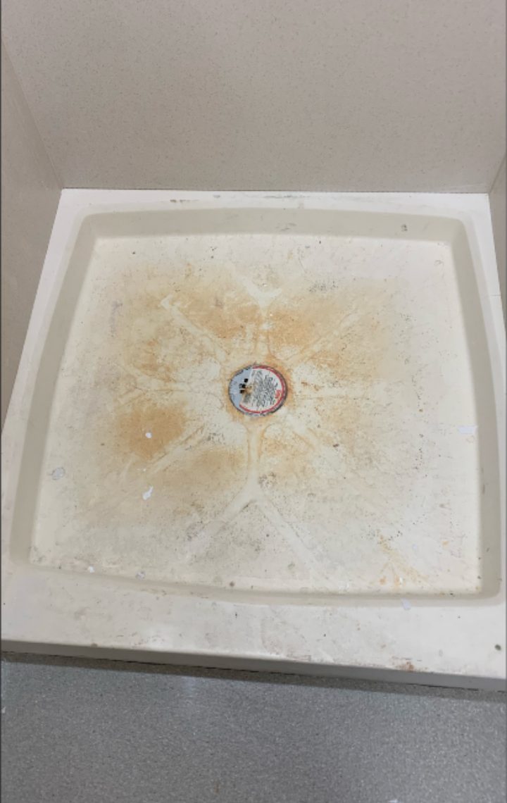 Before cleaning — rust-stained shower pan